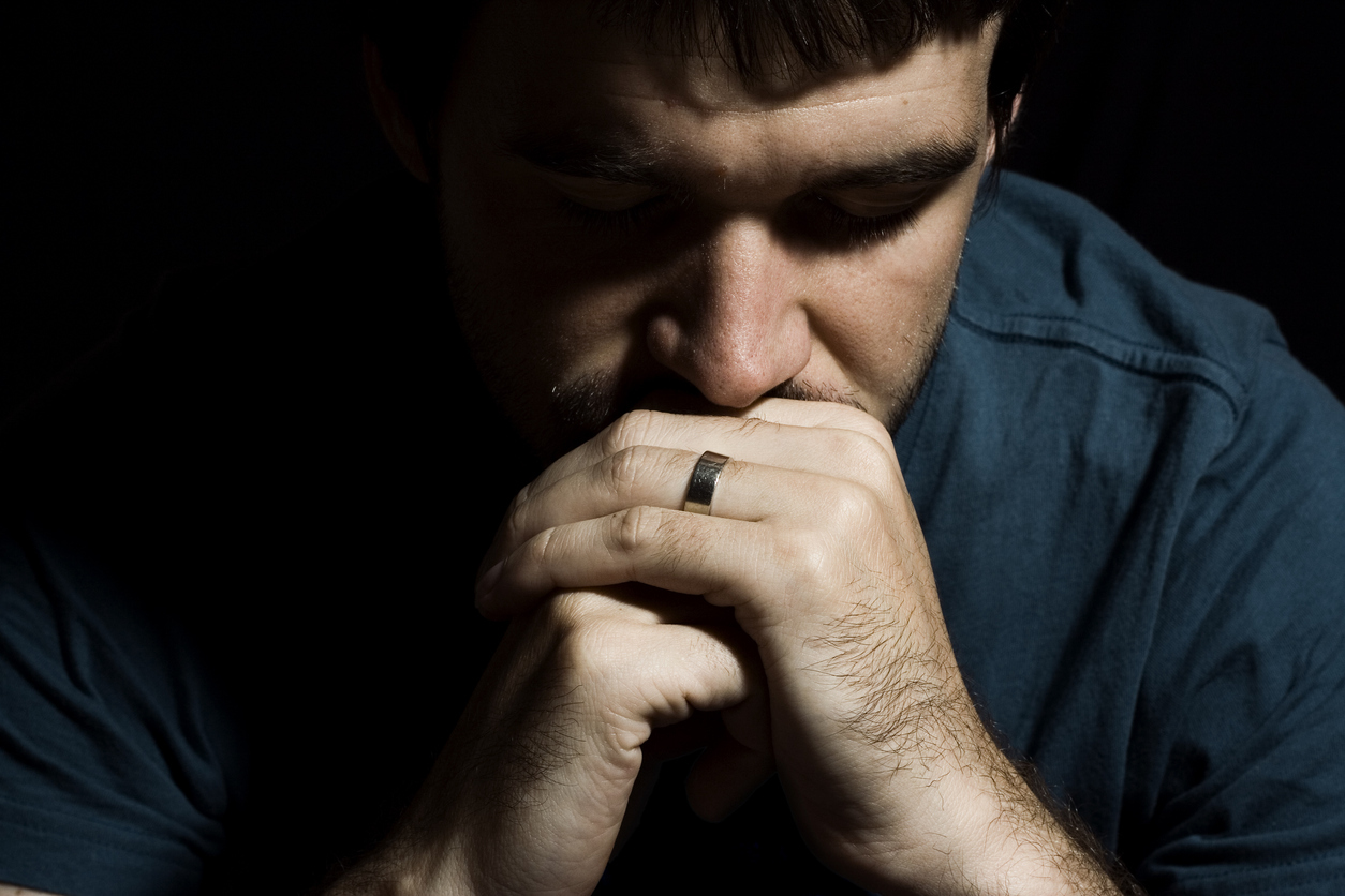 A young man with his chin resting on his hands deep in thought