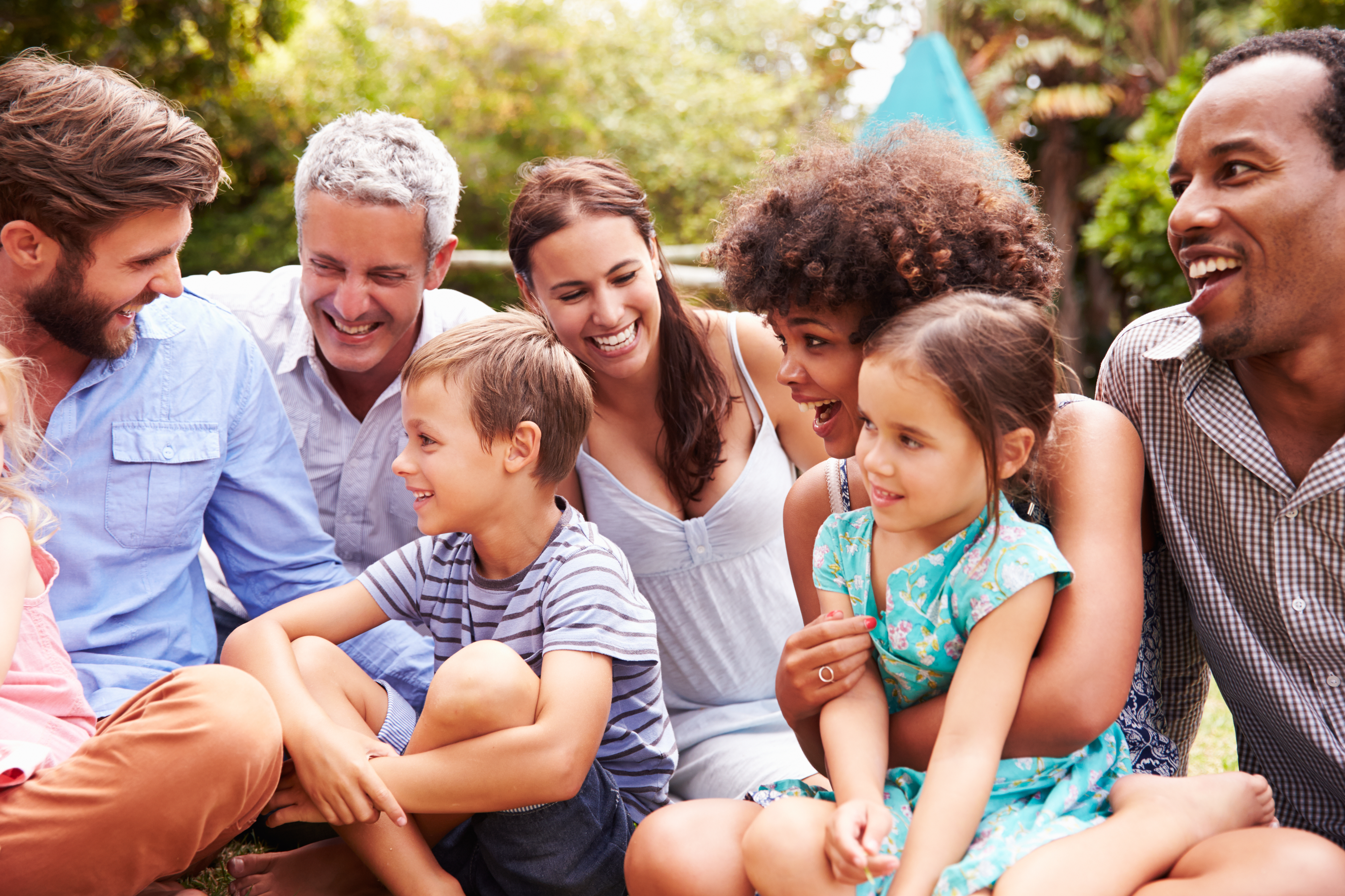 Adults and children sitting on the grass in a garden