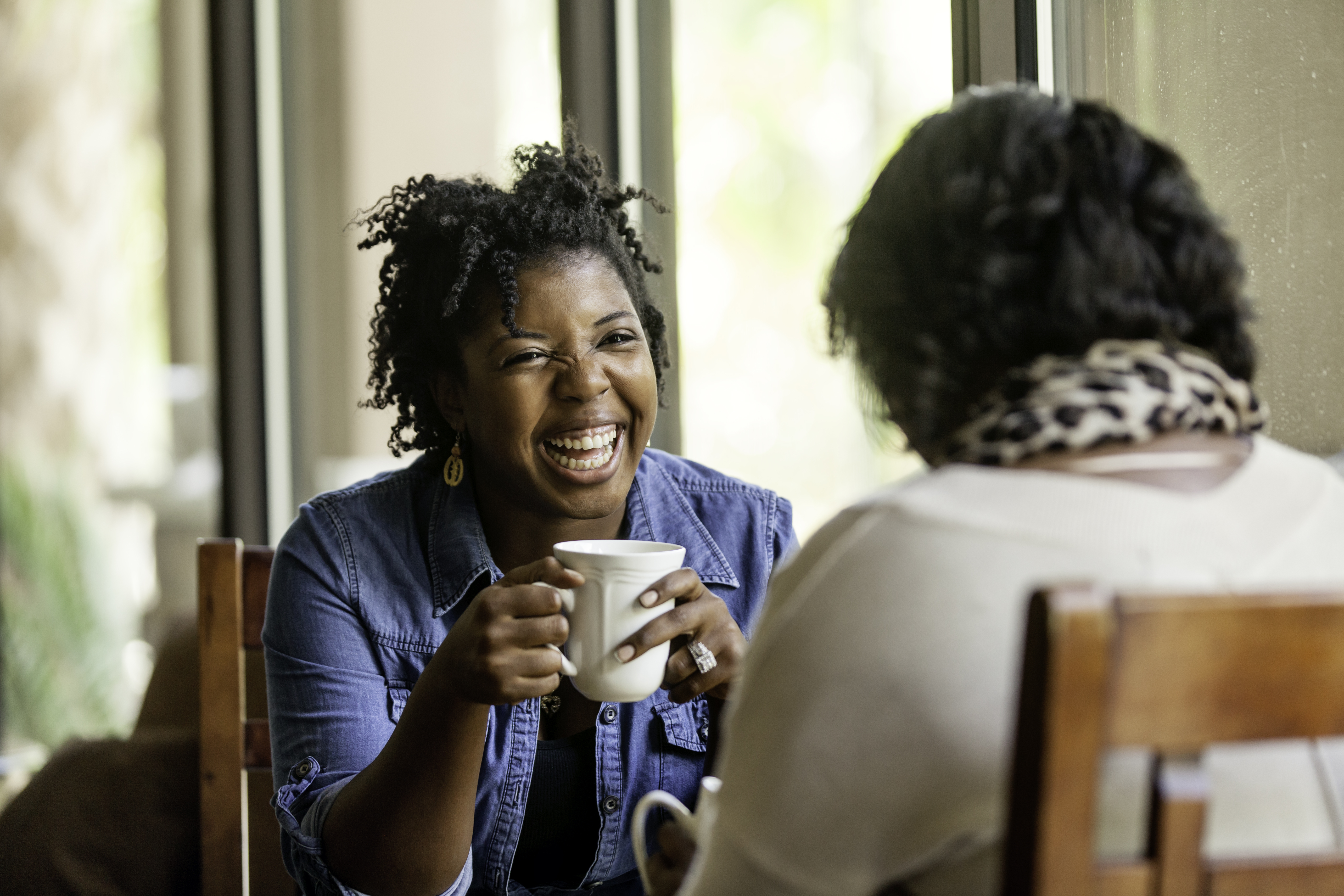 African American woman has a good time with a close friend drinking coffee