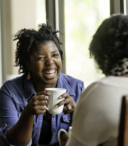 African American woman has a good time with a close friend drinking coffee