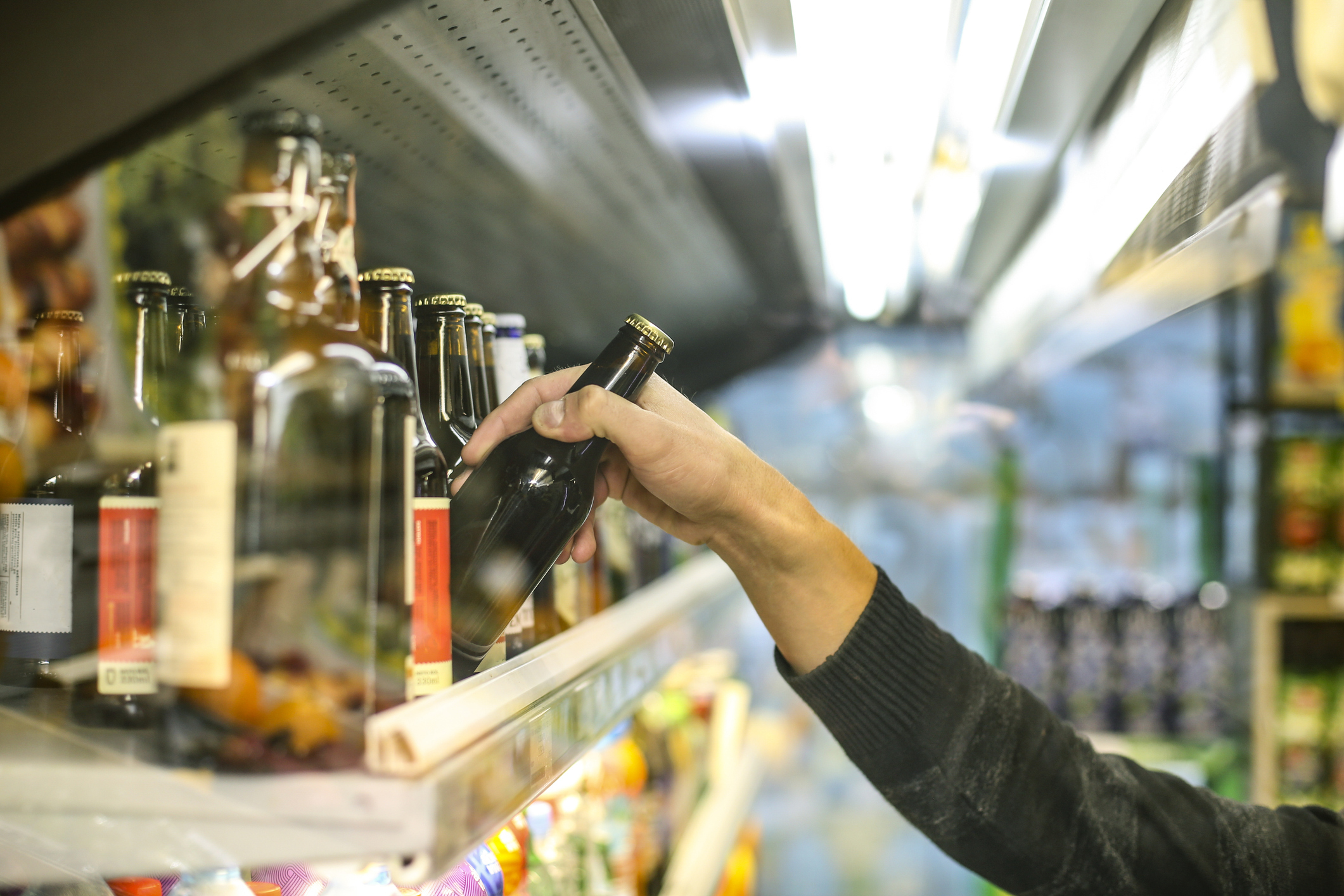 Unrecognisable man selecting alcohol from a supermarket shelf
