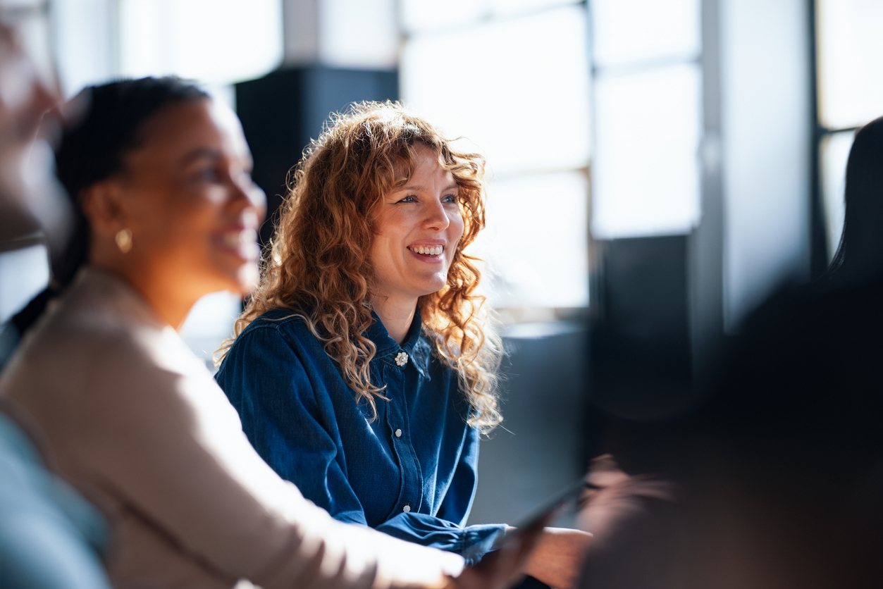 Two smiling colleagues engaging in informal discussion at work in brightly lit space