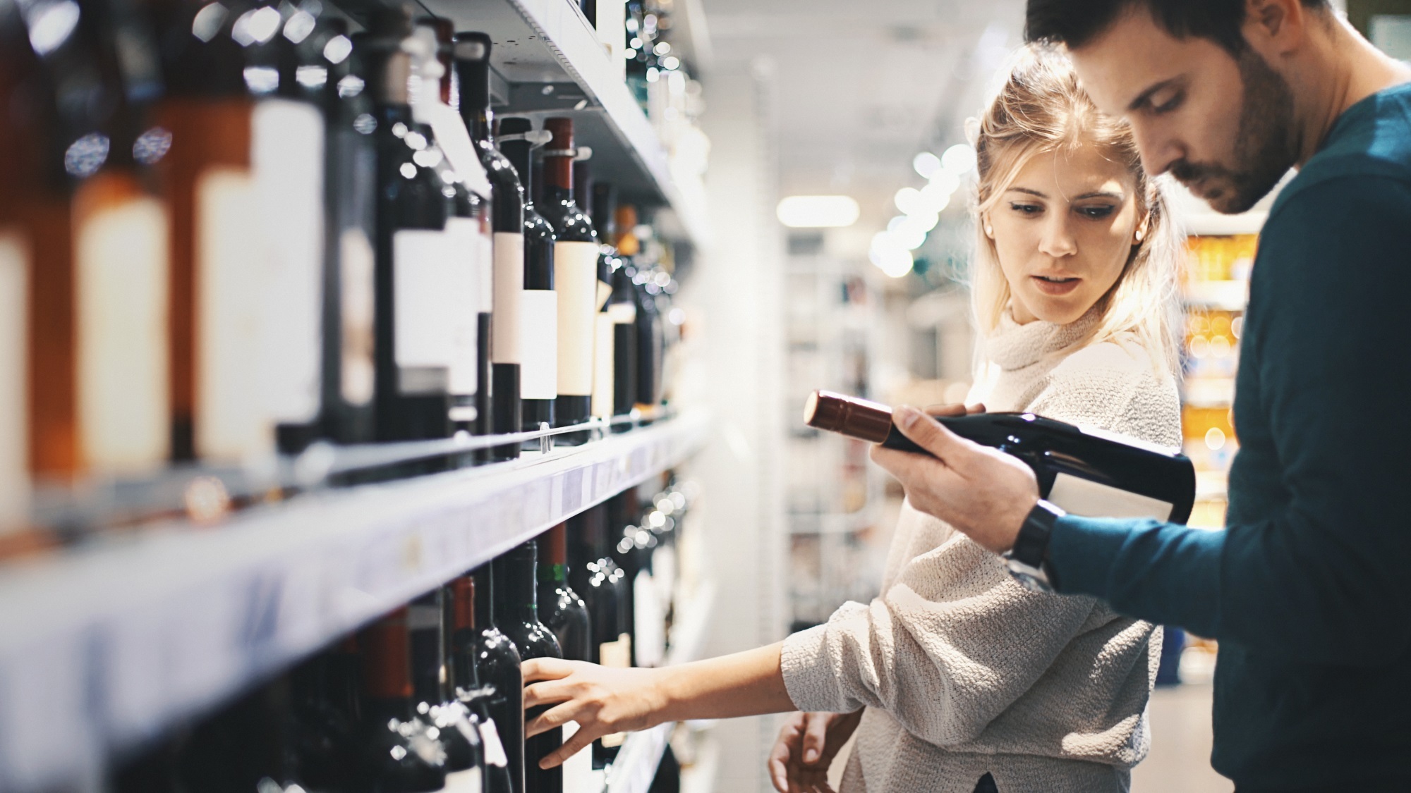 A couple buying some wine at a supermarket.