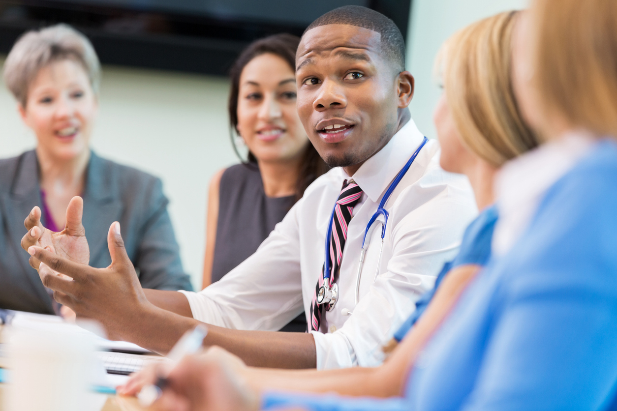 Doctor sitting at boardroom table talking with colleagues during a meeting