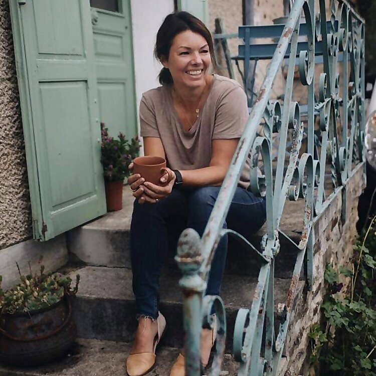 A woman holding a coffee cup sits on an ornate outdoor staircase.