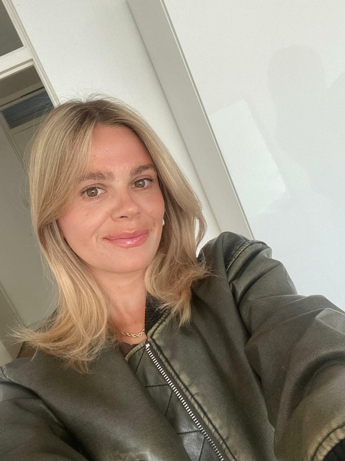 A woman with straight, blonde hair takes a selfie.