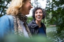 Happy mature woman looking at female friend while walking in forest