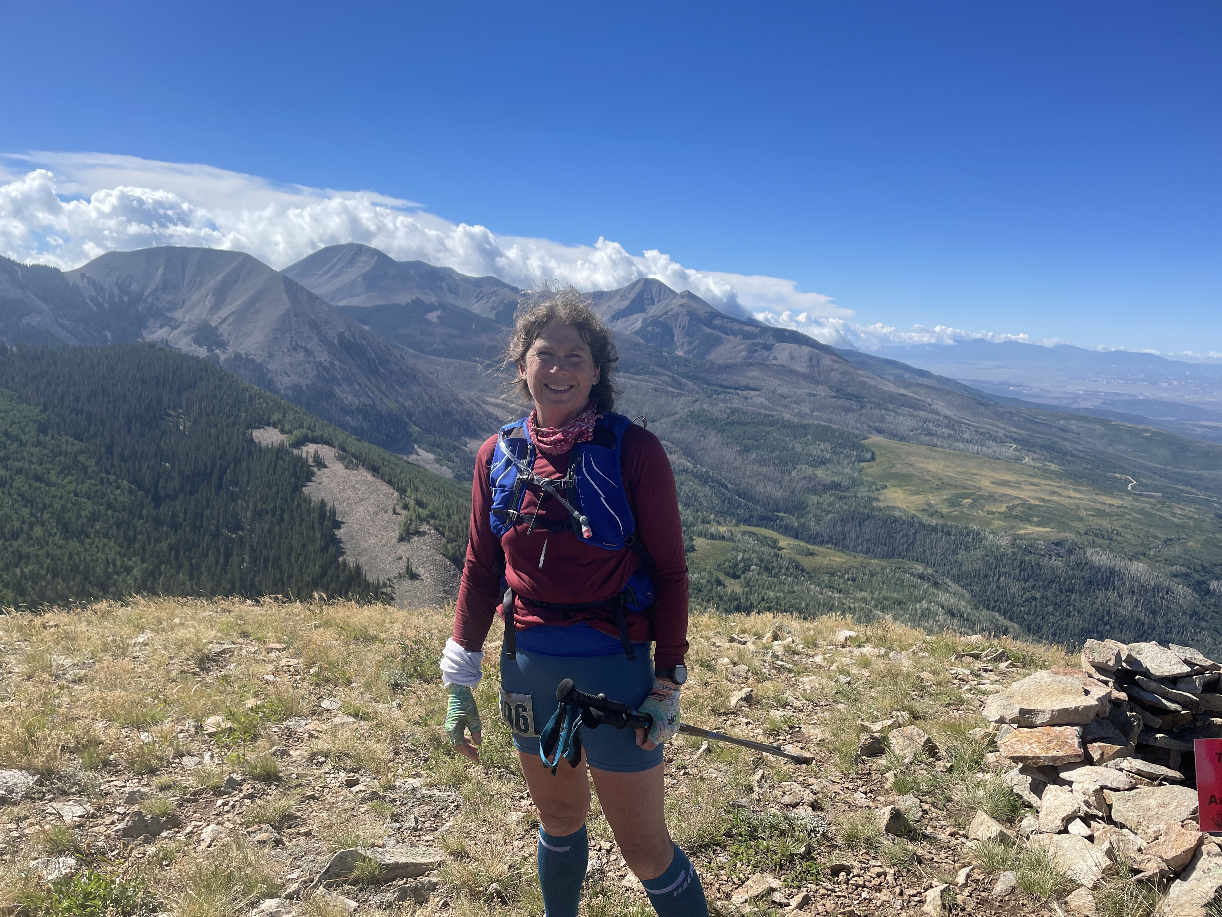 A woman wearing shorts and hiking gear stands on top of a mountain range.