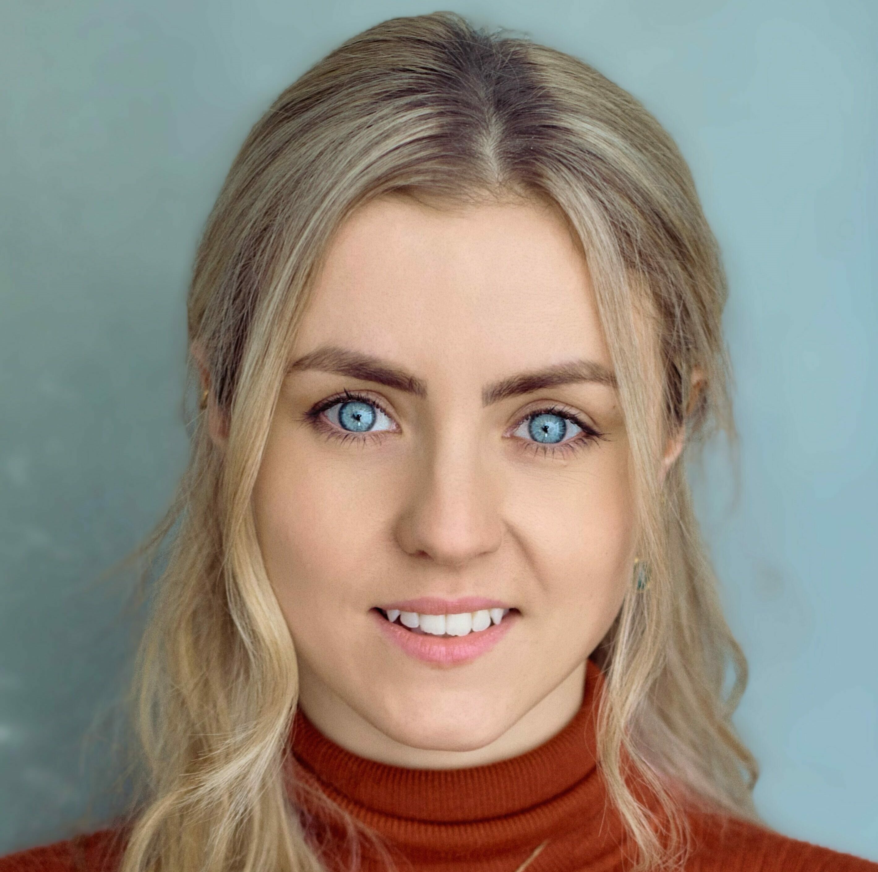 A young woman with blonde hair and blue eyes smiles at the camera.