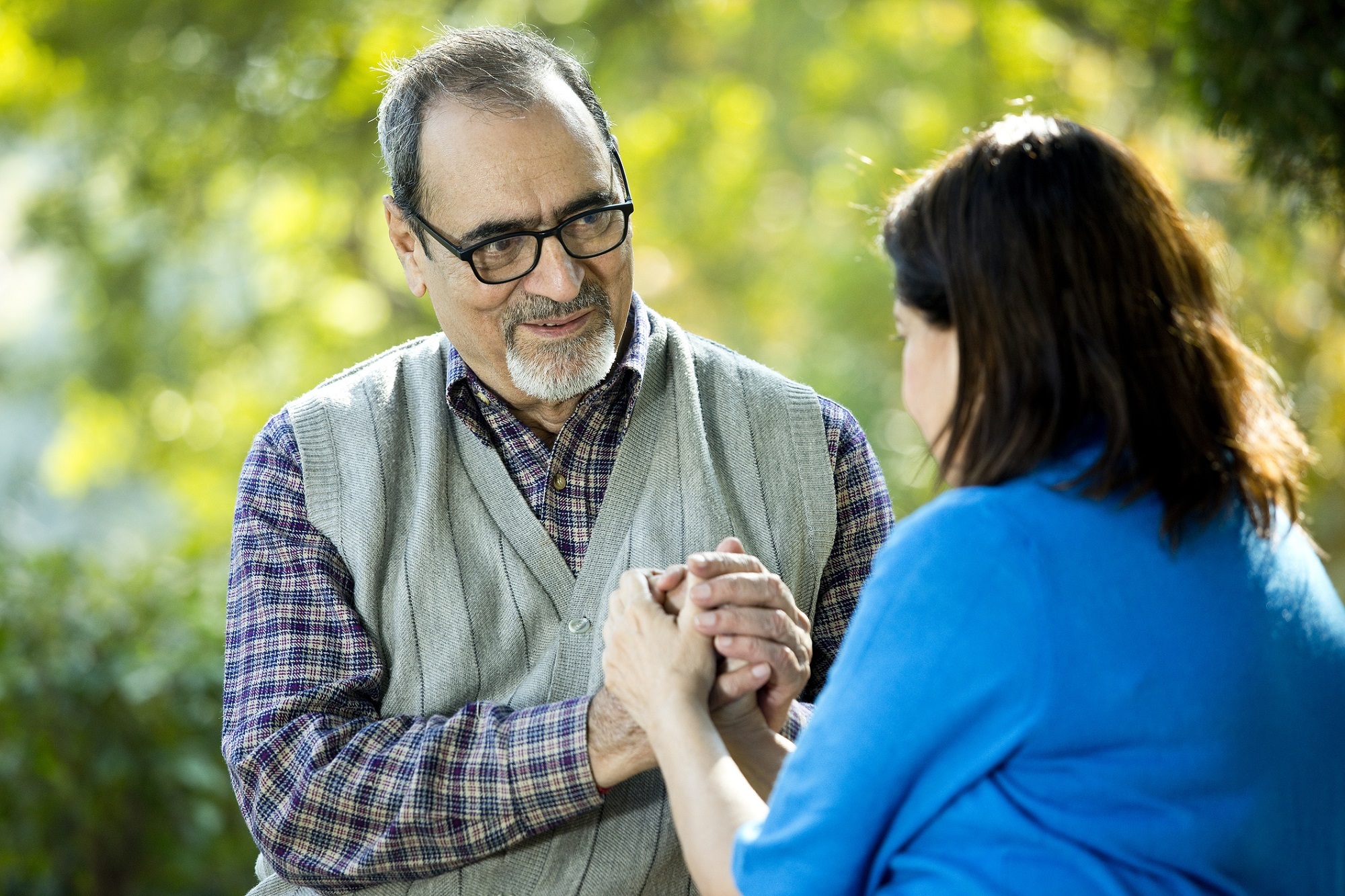 Loving senior man holding hands of his wife at park