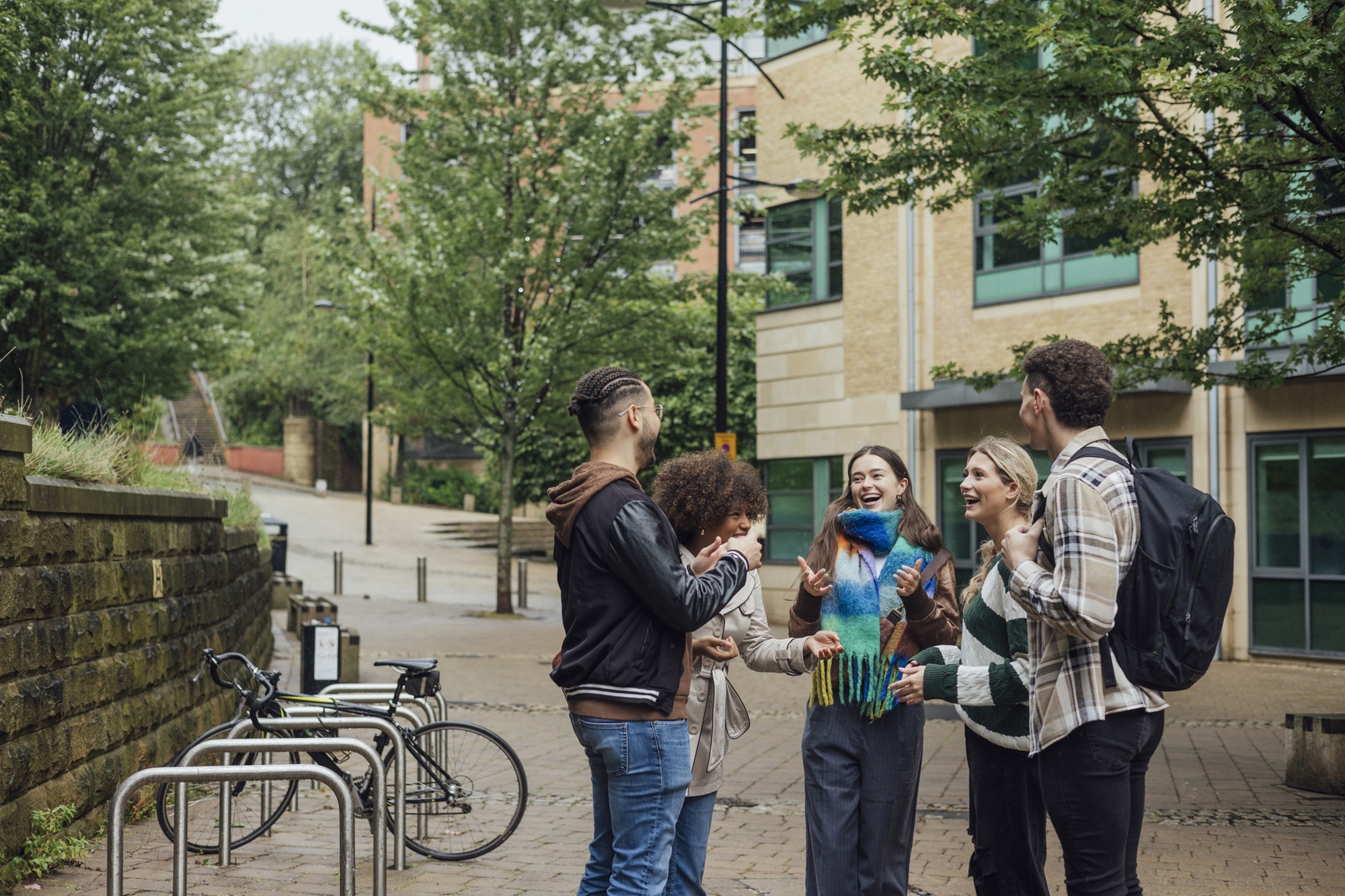 A wide view of a small group of university students standing together talking in the city on an autumn day