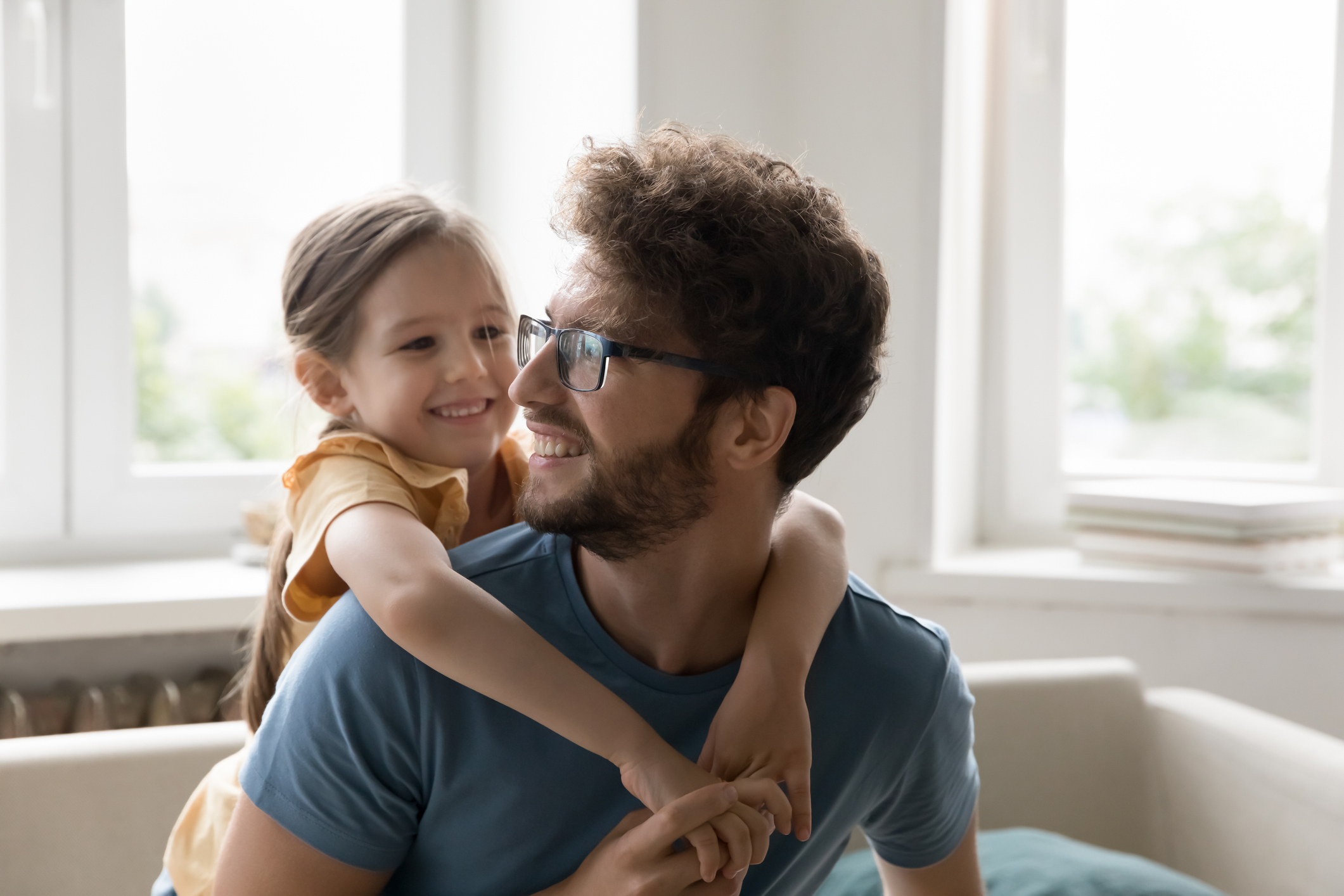 Man gives a young child a piggy back while they both laugh.