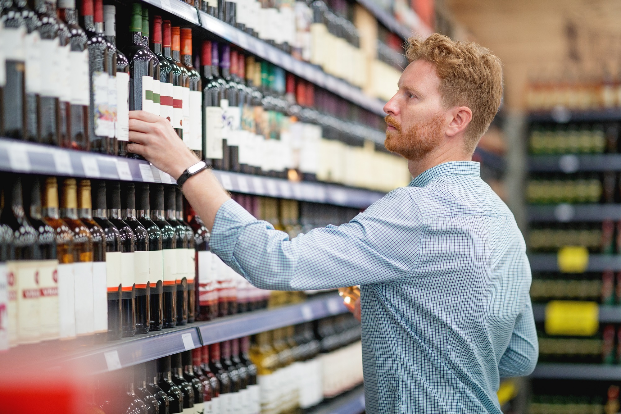 Man picking up wine in supermarket