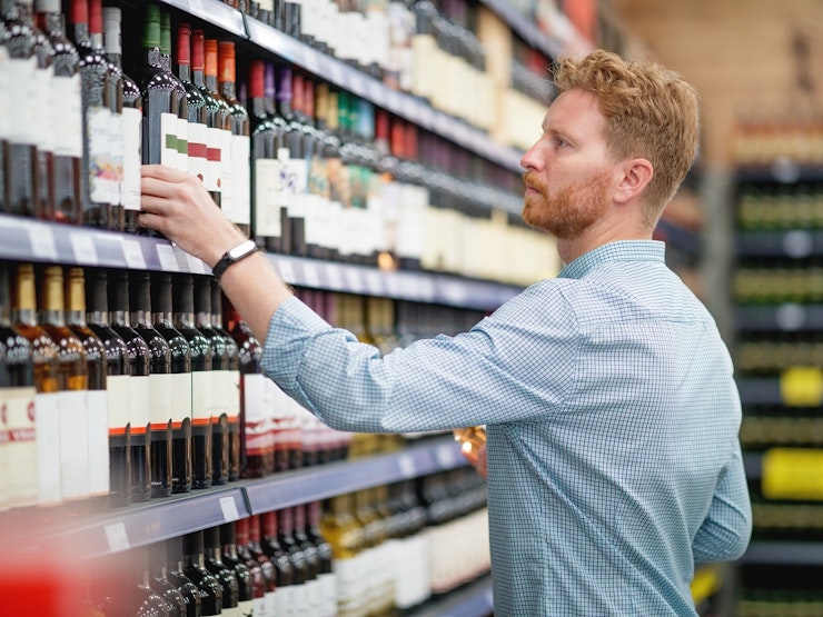 Man picking up wine in supermarket