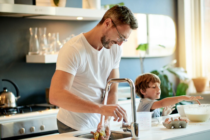 Man standing at kitchen sink with son