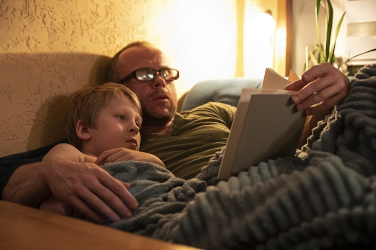 Man wearing glasses reads a child story by bedside light i Stock 1400806778 2 K px