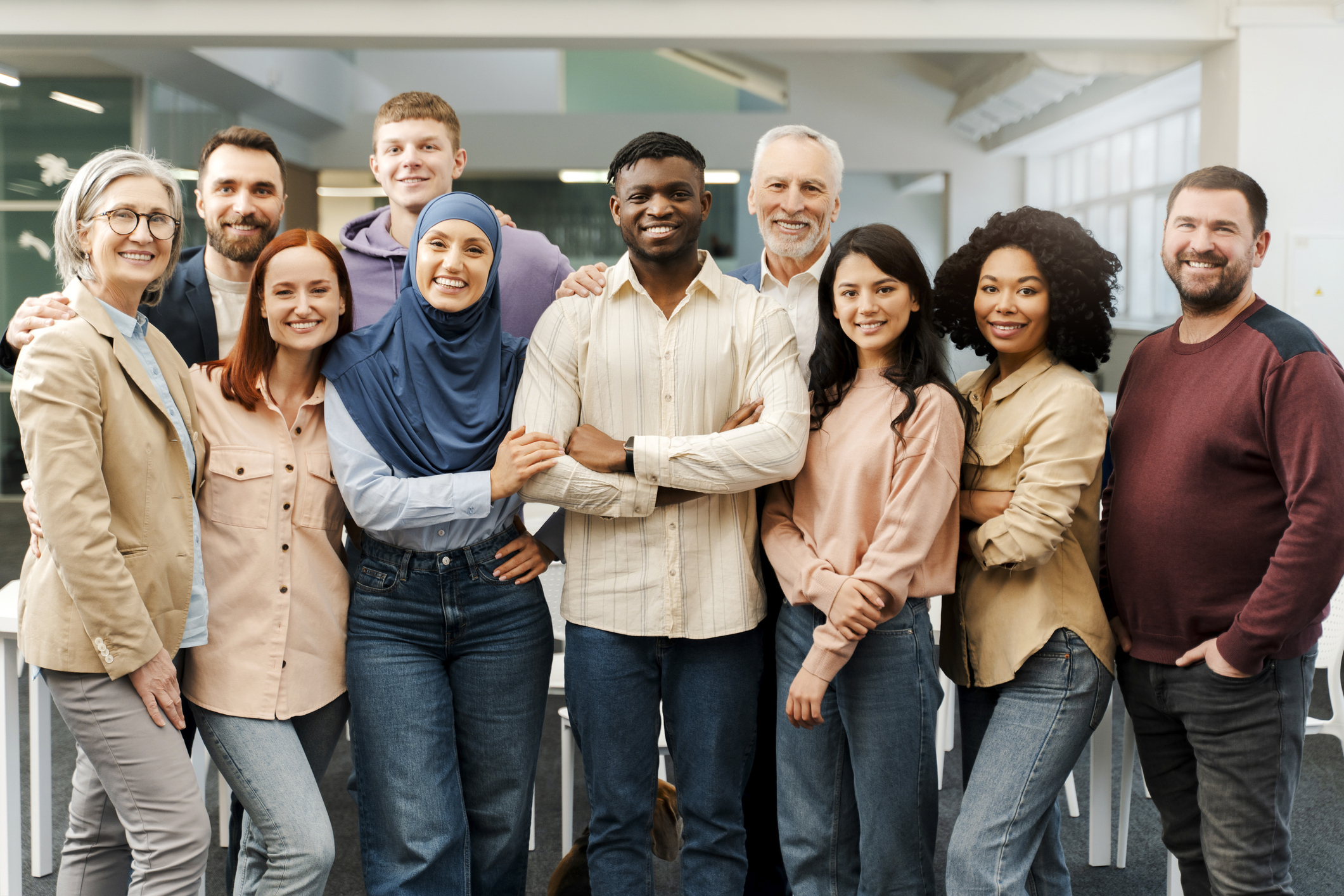 Mixed portrait of smiling business people looking at camera standing in modern office.