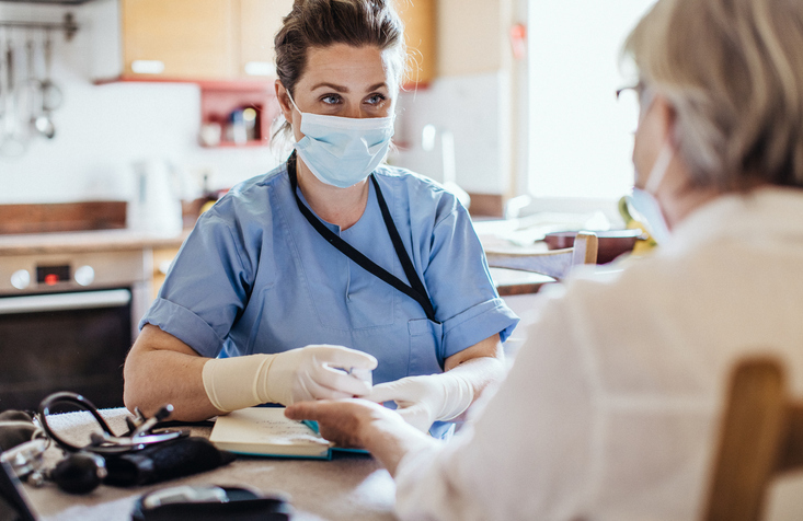 Nurse at home assisting middle aged woman