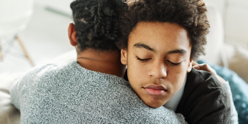 Portrait of son hugging his parent, together at home, with hand on his shoulder comforting him.