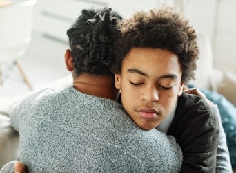 Portrait of son hugging his parent, together at home, with hand on his shoulder comforting him.