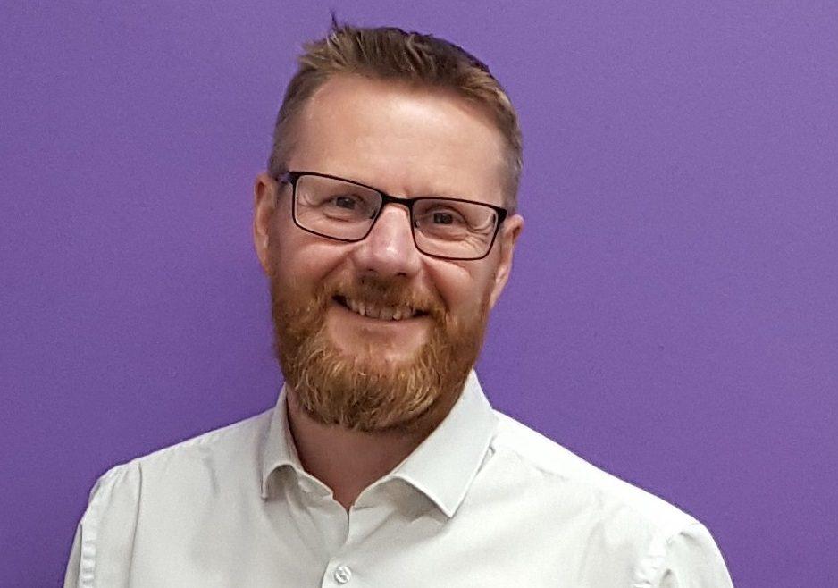 A man in a white shirt smiles.