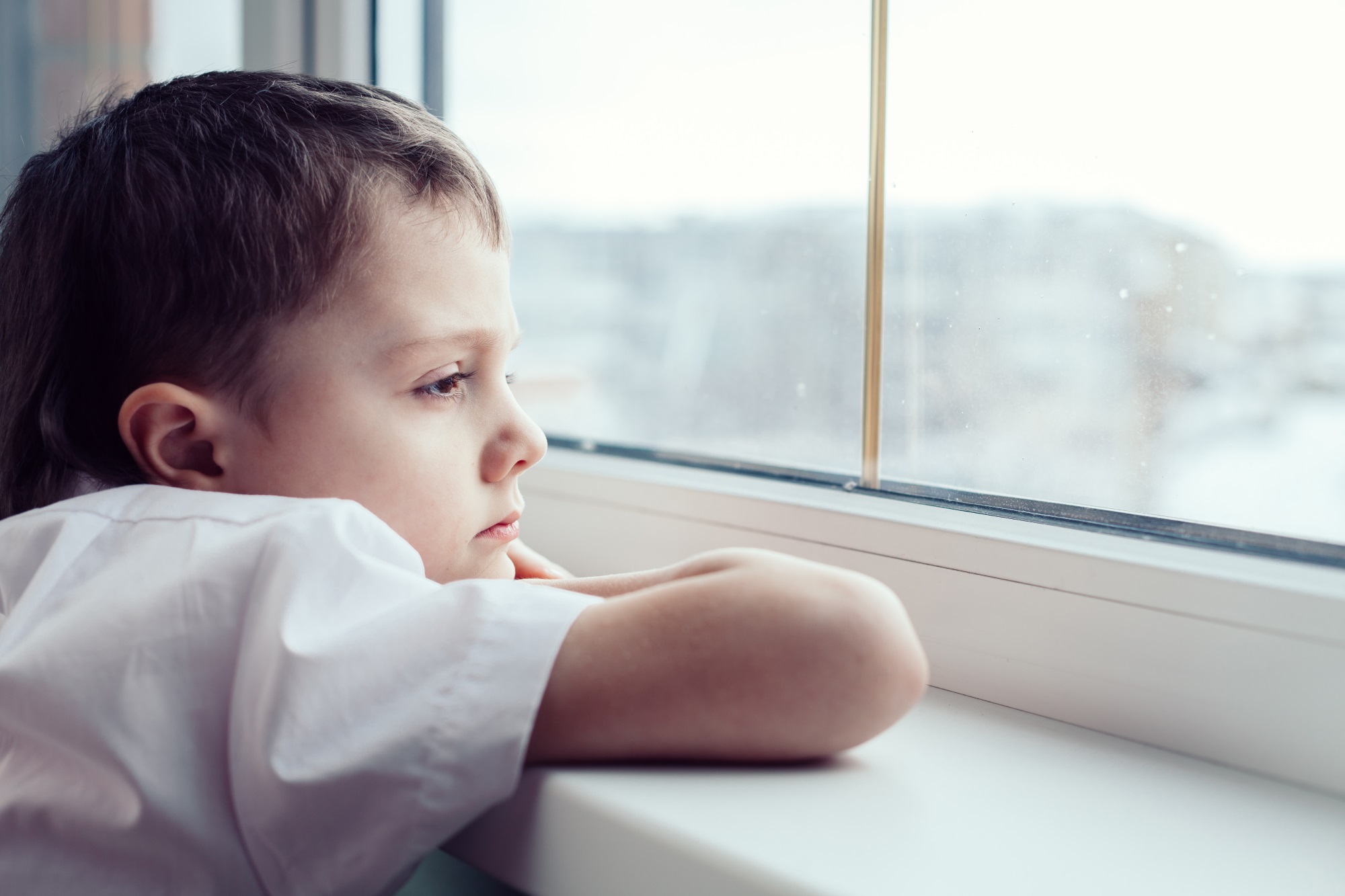 Sad Little Boy Sitting Near The Window Istock 886423602