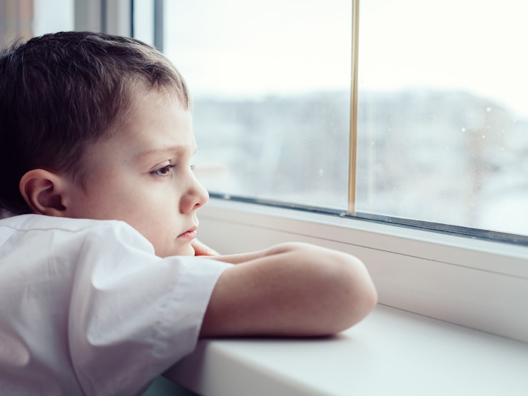 Sad Little Boy Sitting Near The Window Istock 886423602