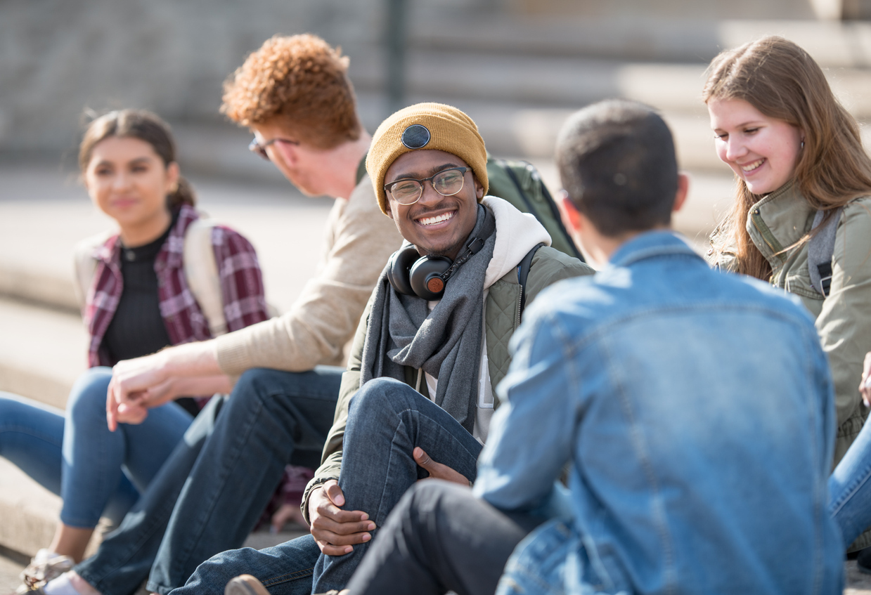 Grpup of students smiling and hanging out on campus on stone steps