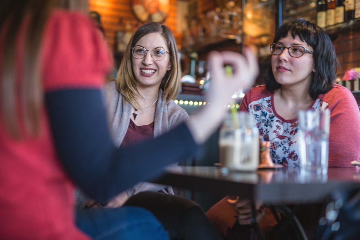 Three young women sitting down in a pub engrossed in conversation