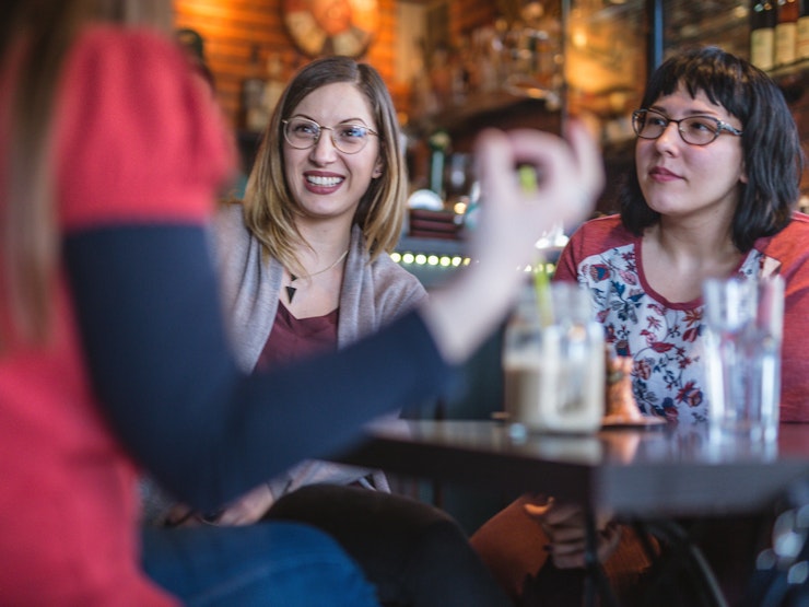 Three young women sitting down in a pub engrossed in conversation
