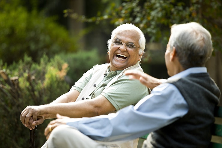 Two senior men chatting on park bench