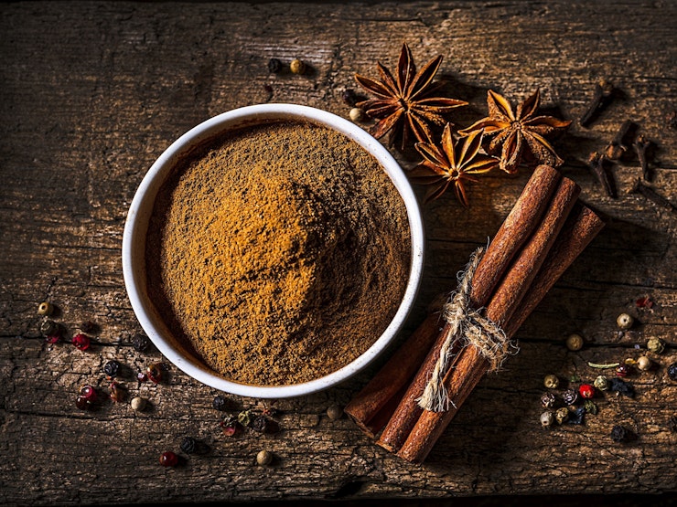 Whole and ground cinnamon and whole Star Anise laid on a wooden table.