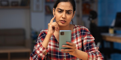 Young woman looking confused checking something on her phone