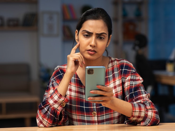 Young woman looking confused checking something on her phone