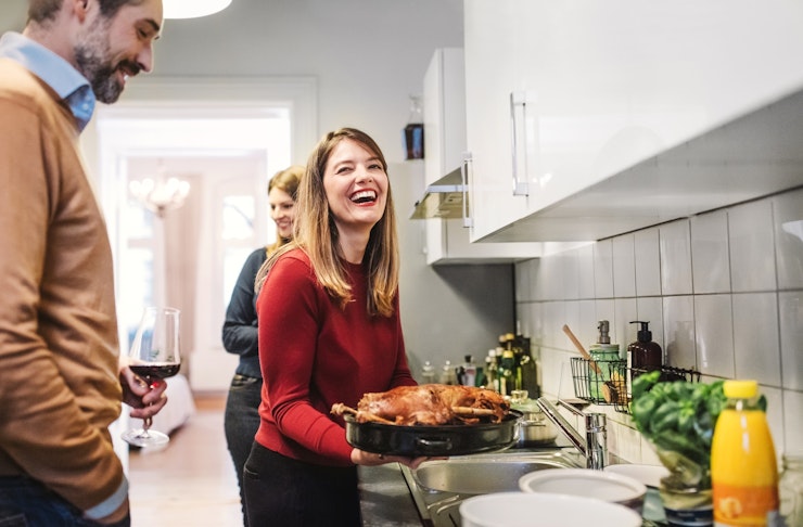 Young Woman Smiling And Holding Christmas Poultry In Kitchen Istock 870412366
